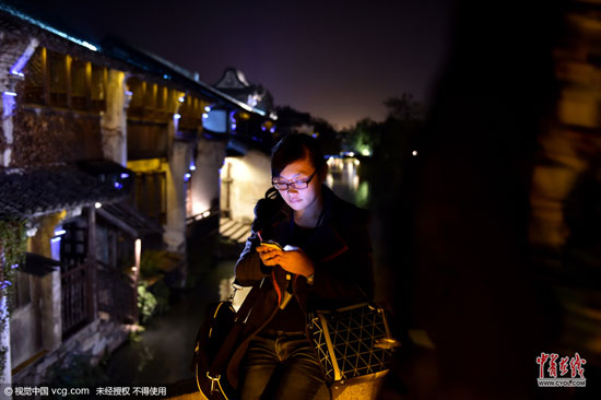 不管白天還是夜里，行走在烏鎮(zhèn)老街上，處處可見上網(wǎng)的人群。(圖片作者：梁臻)